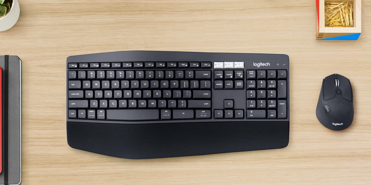 Logitech MK850 wireless keyboard and mouse combo on a desk between a Windows PC and a Mac